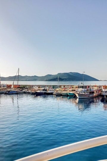 Kaş harbour wall with lighthouse. The rails of the ferry are in the foreground.