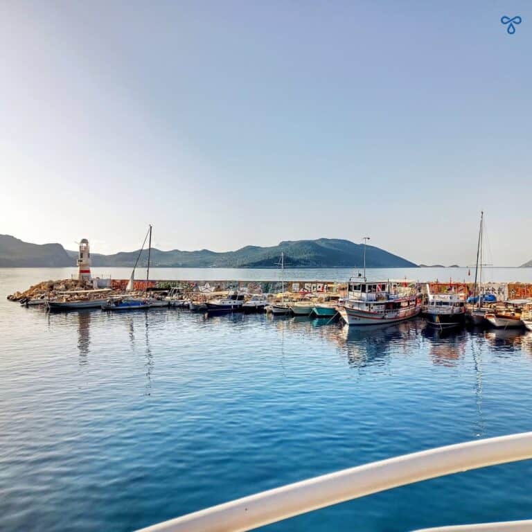 Kaş harbour wall with lighthouse. The rails of the ferry are in the foreground.