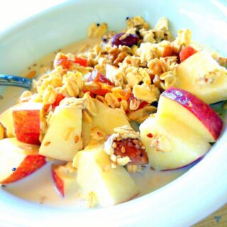 Apple chınks and muesli in a bowl of milk.
