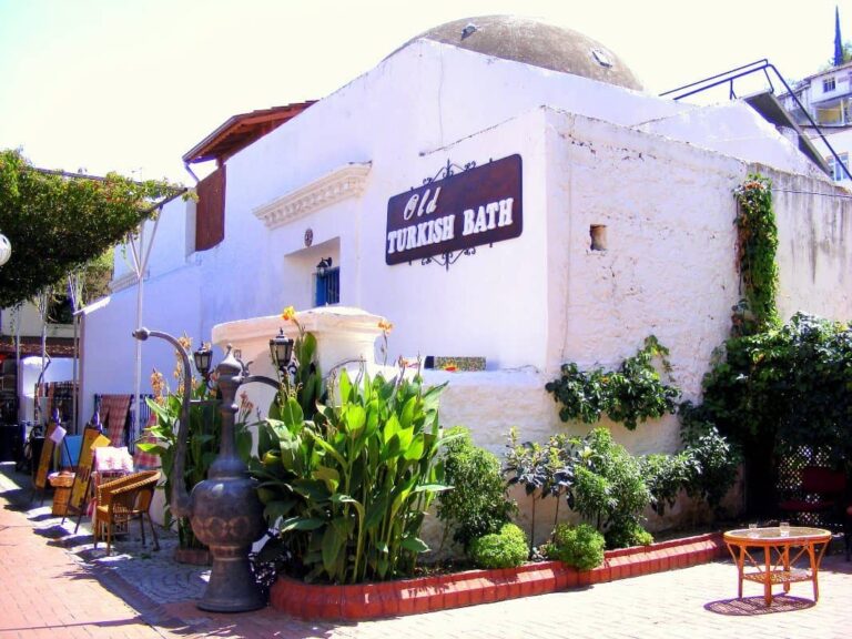 A historic whitewashed hamam in Fethiye. Green plants are at the entrance and the sign reads Old Turkish Bath