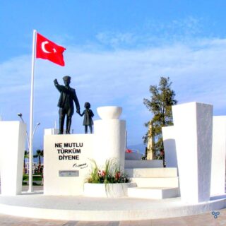 Statue of Atatürk and child. The Turkish flag flies next to it.