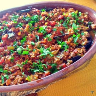 Clay pot with musakka and fresh, chopped green herbs
