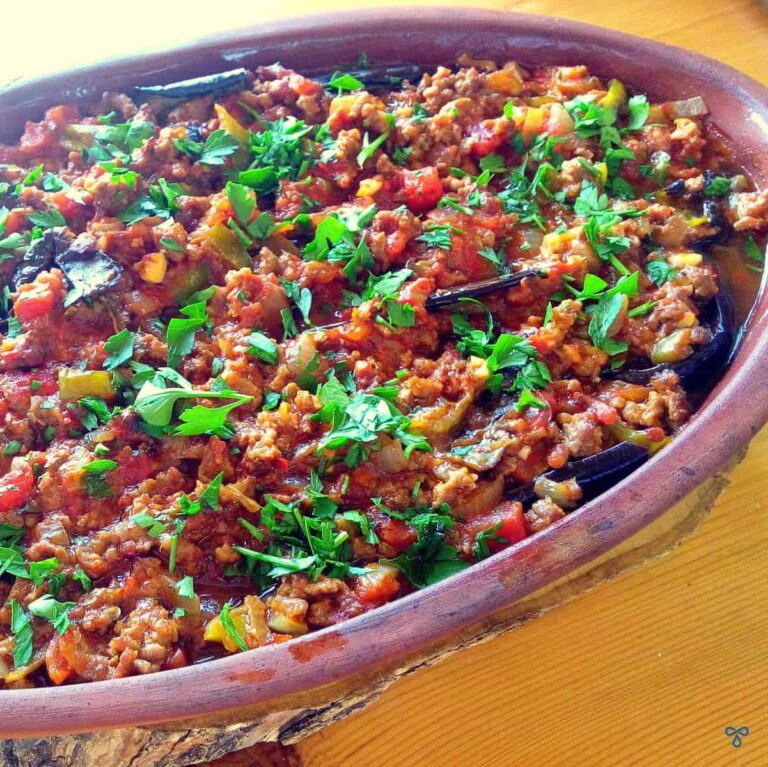 Clay pot with musakka and fresh, chopped green herbs