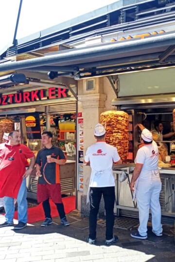Meat and chicken döner kebab rotating in Istanbul. The staff stand outside, chatting