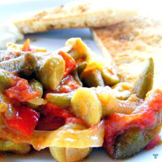 Baby okra in a tomato sauce. Two slices of toasted bread are in the background.