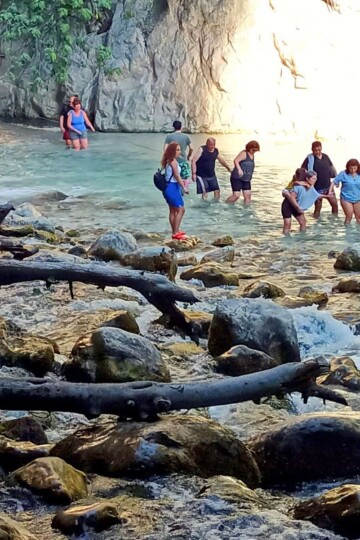 People crossing the rapids at Saklıkent Gorge to continue walking the route.
