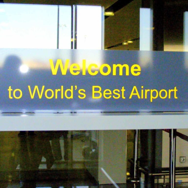 A sign on a glass door reads Welcome to World's Best Airport. The sign is written in yellow lettering.