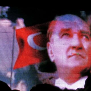 Image of Atatürk with a Turkish flag flying behind him