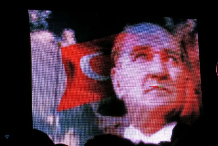 Image of Atatürk with a Turkish flag flying behind him