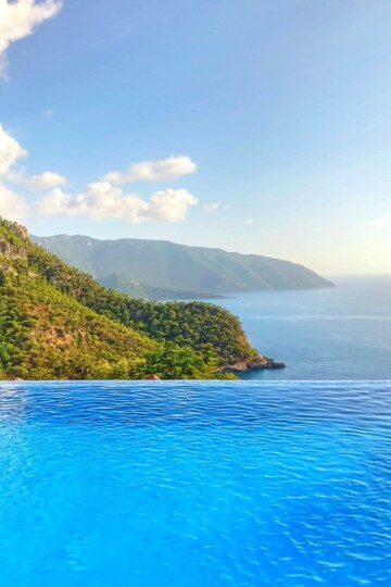 Olive Garden infinity pool looking out over the Mediterranean. A forest clad cliff face is to the left.