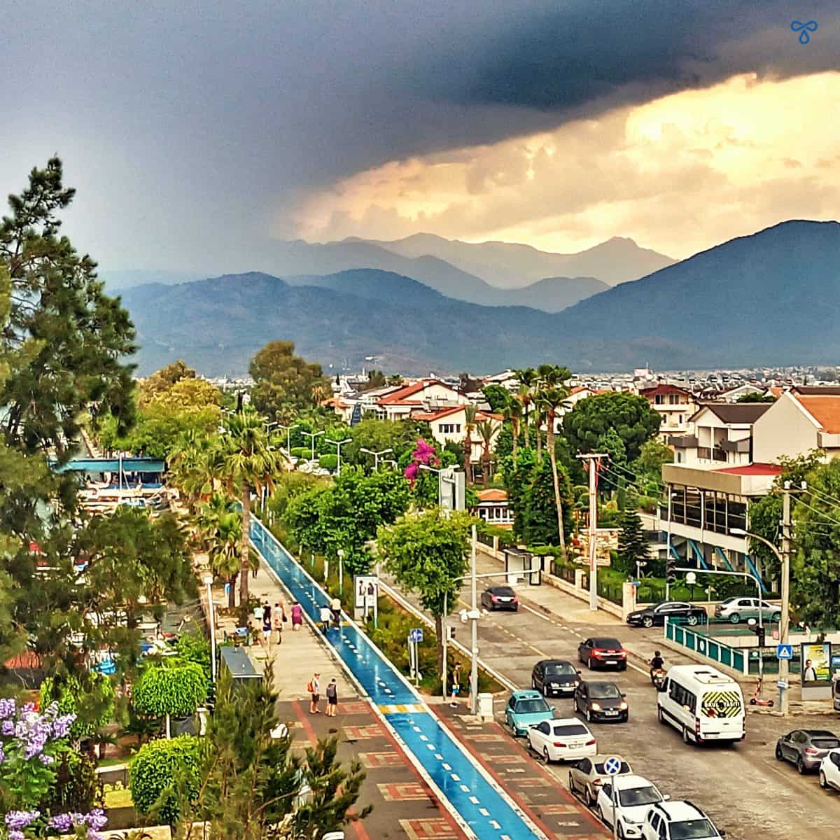 Looking down over the main road in Fethiye from Cafe Park Teras. Rain clouds fill the sky and trees line the road and cycle track.