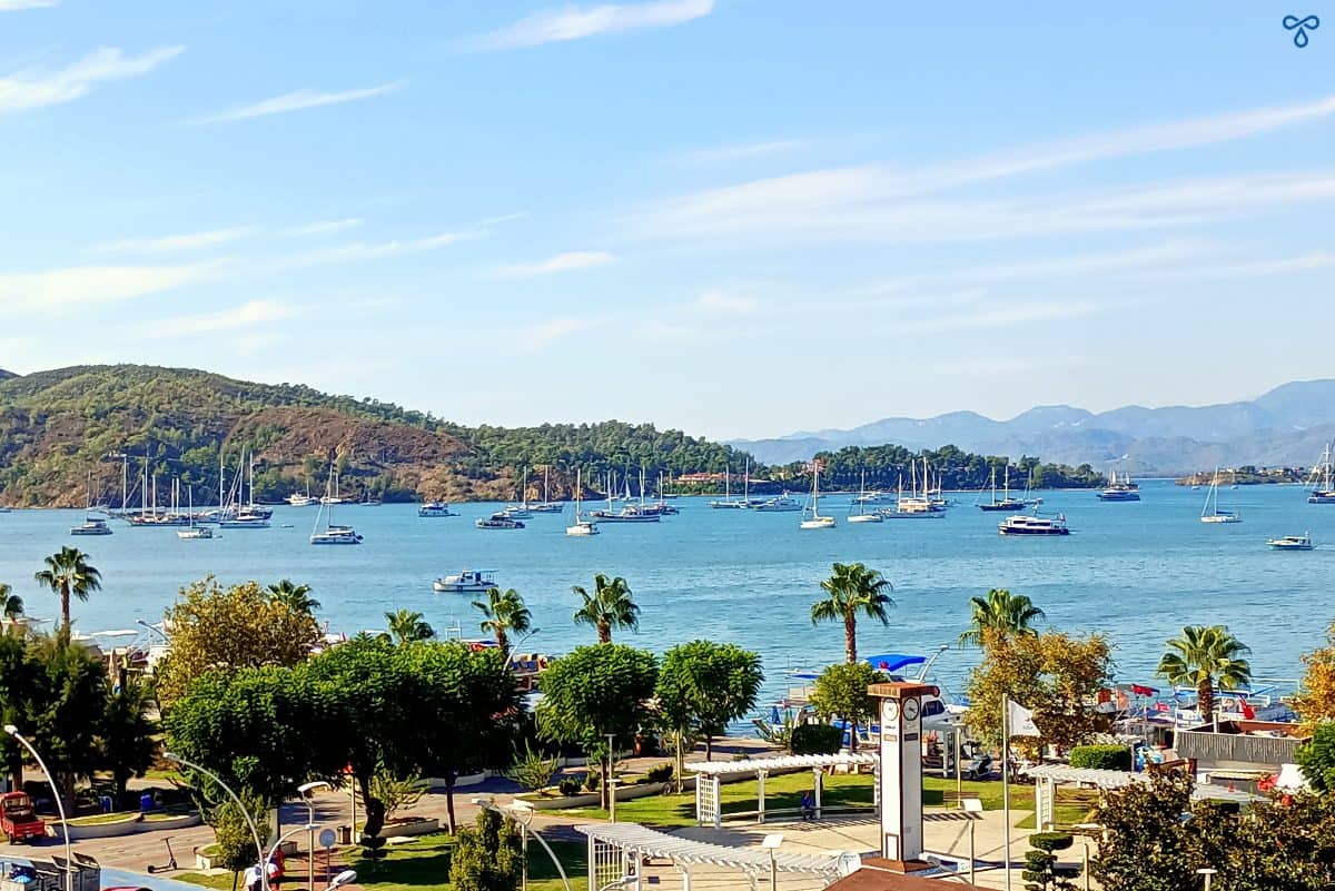 A view of the bay in Fethiye taken from above. Lots of yachts are anchored and a park is in the foreground.