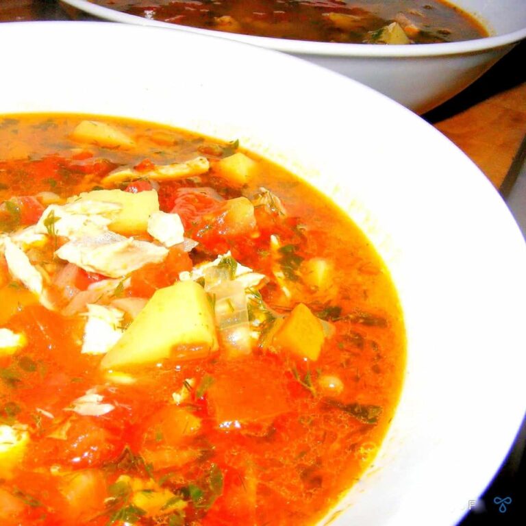 A bowl of soup. A thin stock with carrots, potatoes and pieces of fish