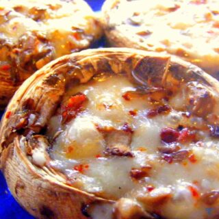 A close up shot of a cooked mushroom stuffed with melted cheese and sucuk.