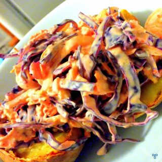 Coleslaw made with red cabbage is piled into a jacket potato