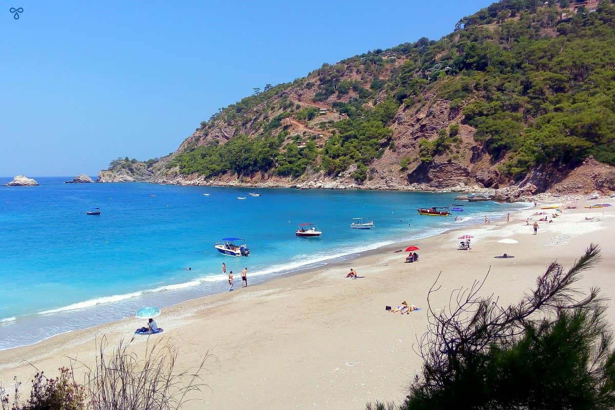 View of the length of Kabak Beach with a handful of people sunbathing and swimming.