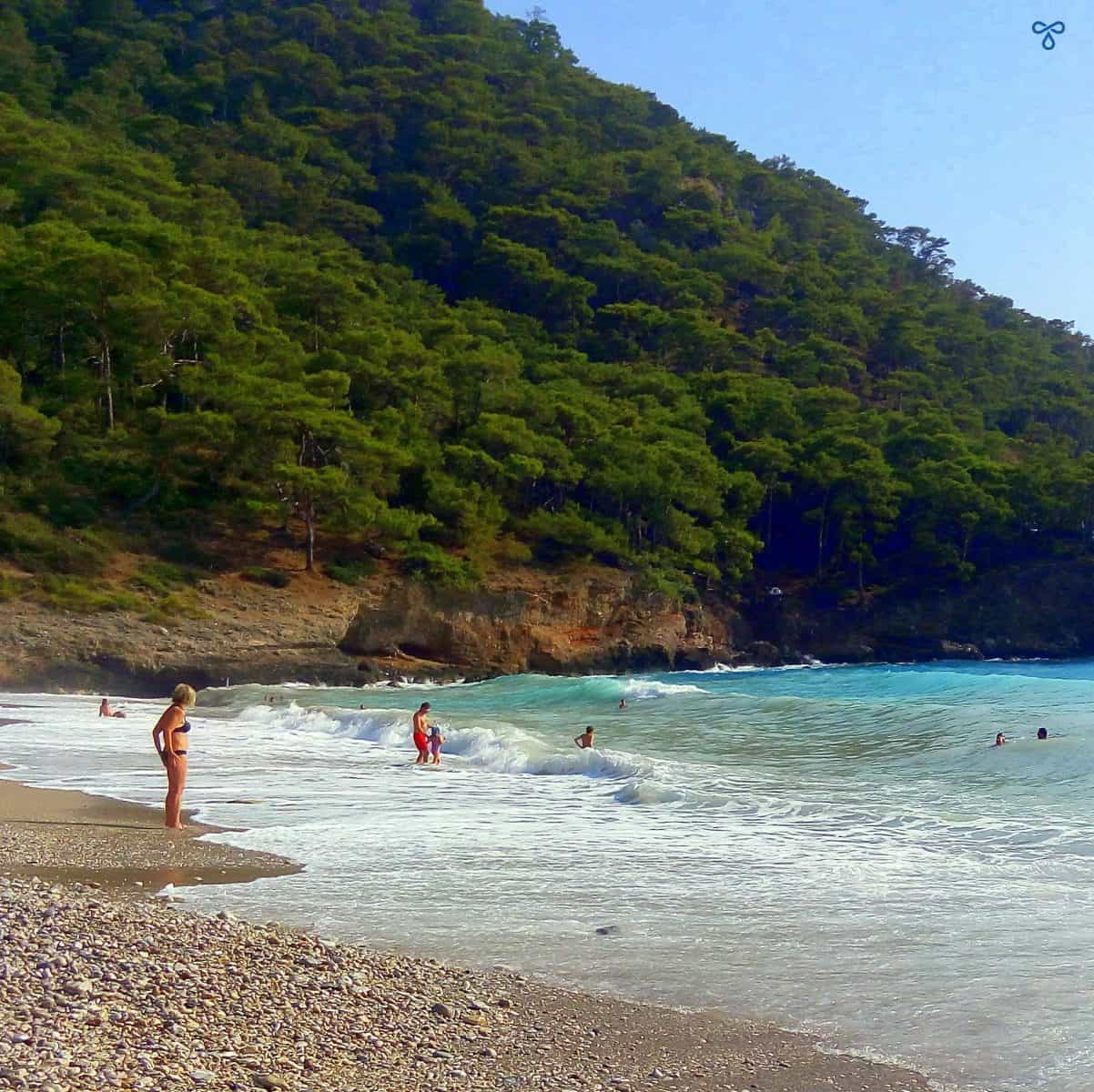 People swimming and paddling in the shallows at Kabak.