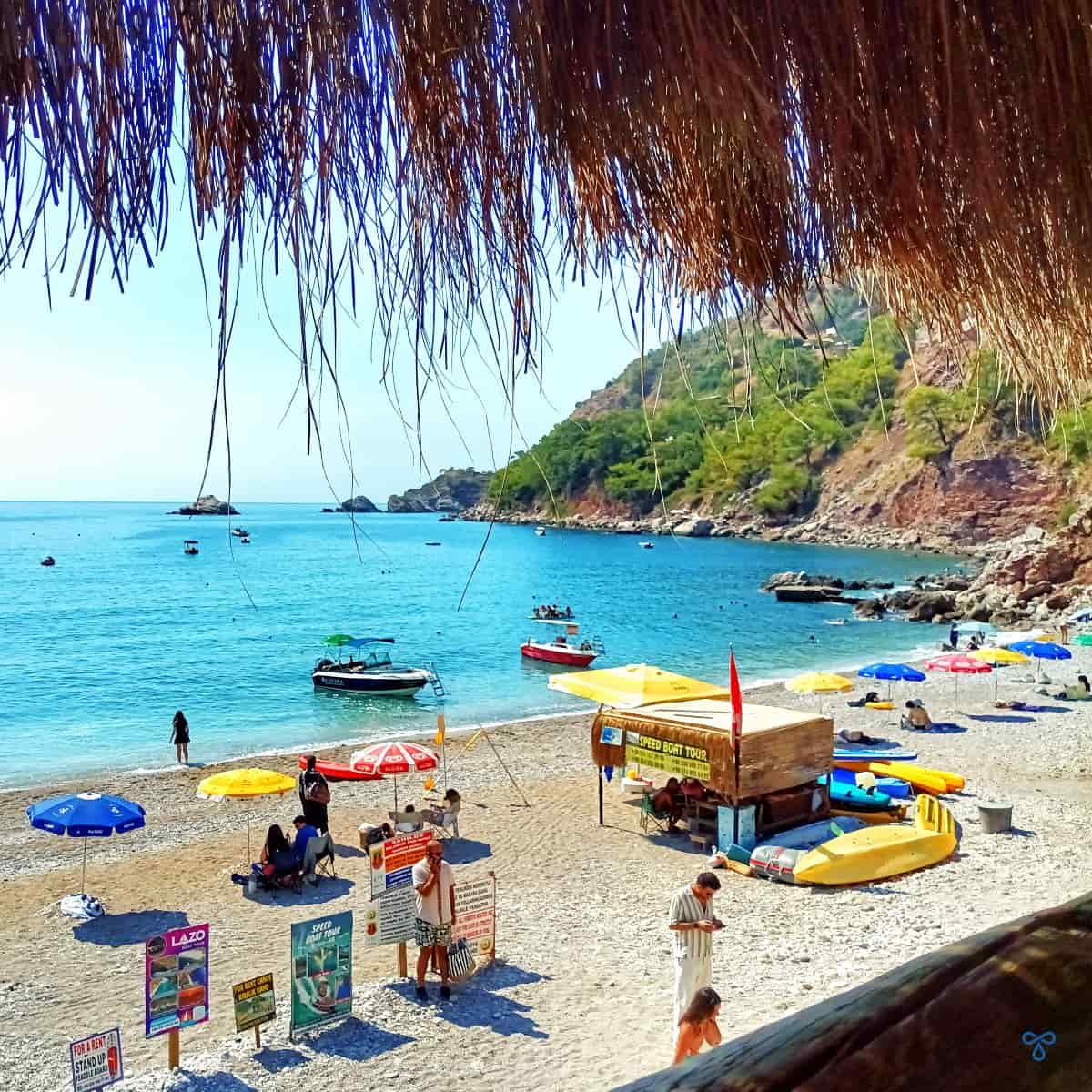 Looking over Kabak Beach. Speed boats are in the sea and signs are on the beach advertising boat trips.