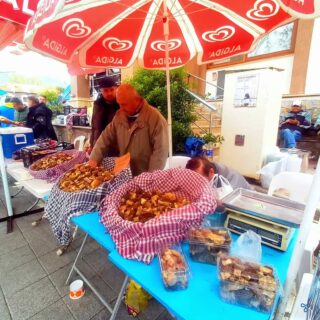 A stall selling morel mushrooms at the Üzümlü Mushroom Festival. The stall is shaded by umbrellas.