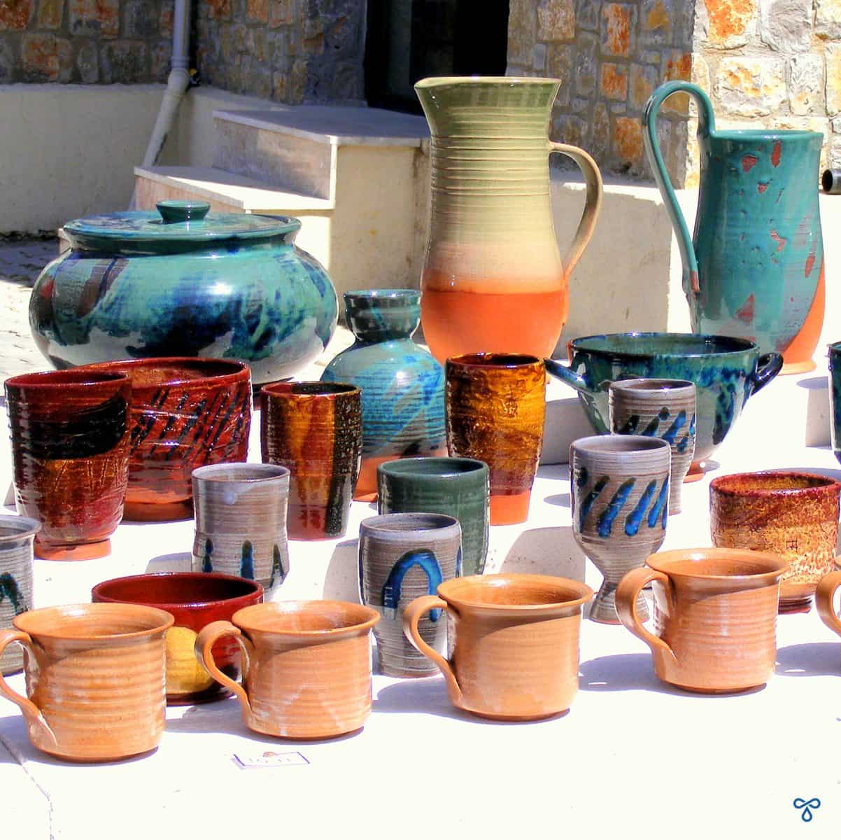 A stall selling handmade ceramics. Cups are on the front row with vases and jugs at the back.