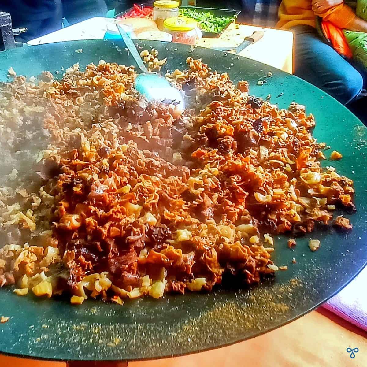 Chopped up morel mushrooms sizzling on a hot plate.