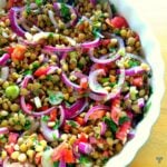 A salad of green lentils with chopped tomato, spring onion and red onion.