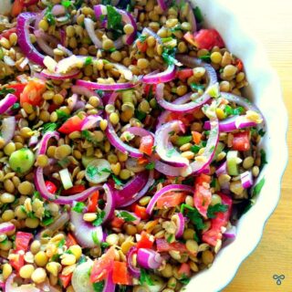A salad of green lentils with chopped tomato, spring onion and red onion.