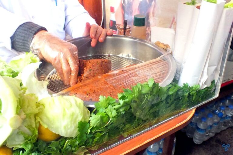 Meat-free çiğ köfte in a circular metal tray. Lettuce, lemon and parsley ring the edge of the tray.