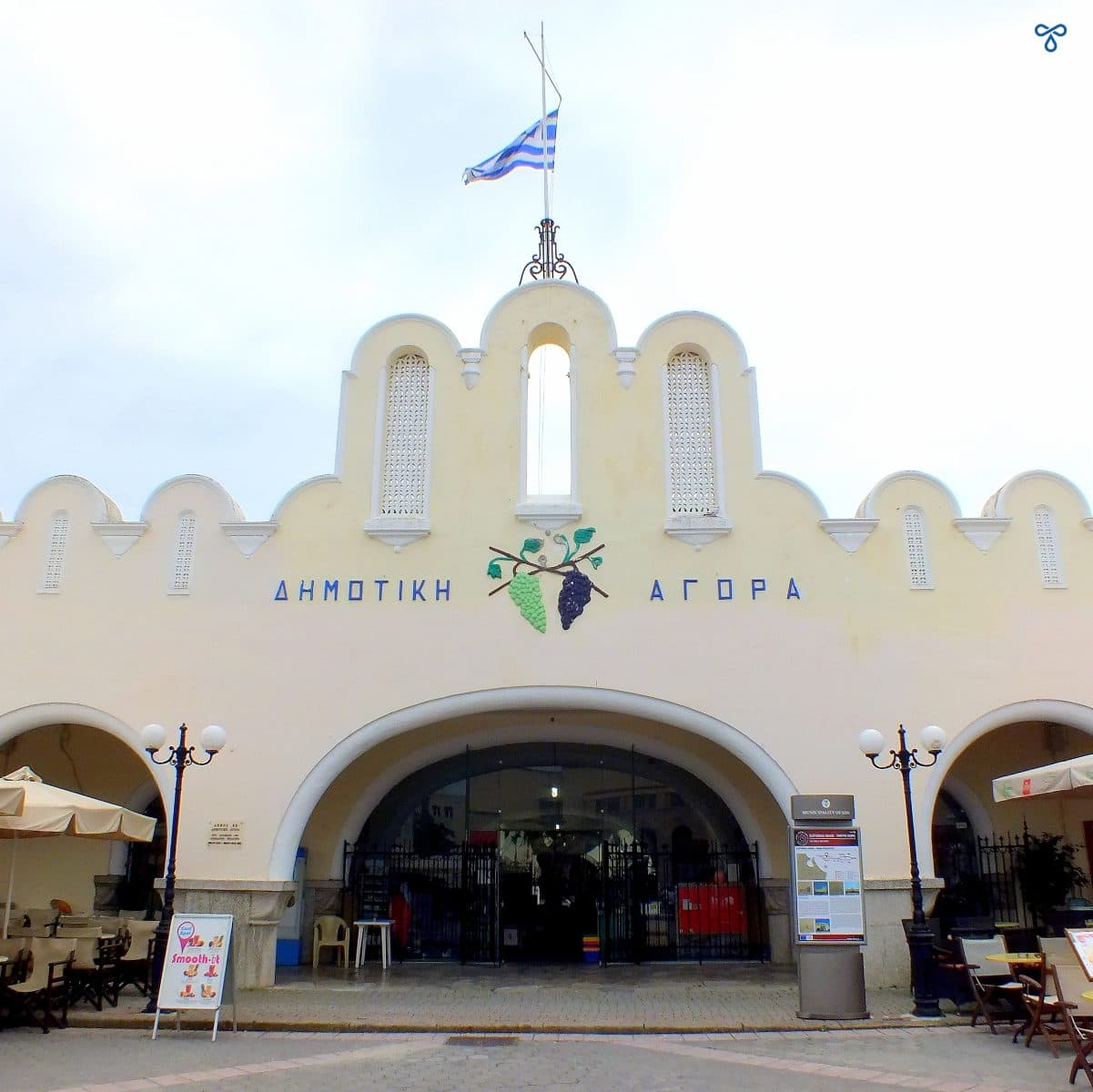 A 1930s art deco building in Kos Town which is the municipal market. A Greek flag flies above the entrance.