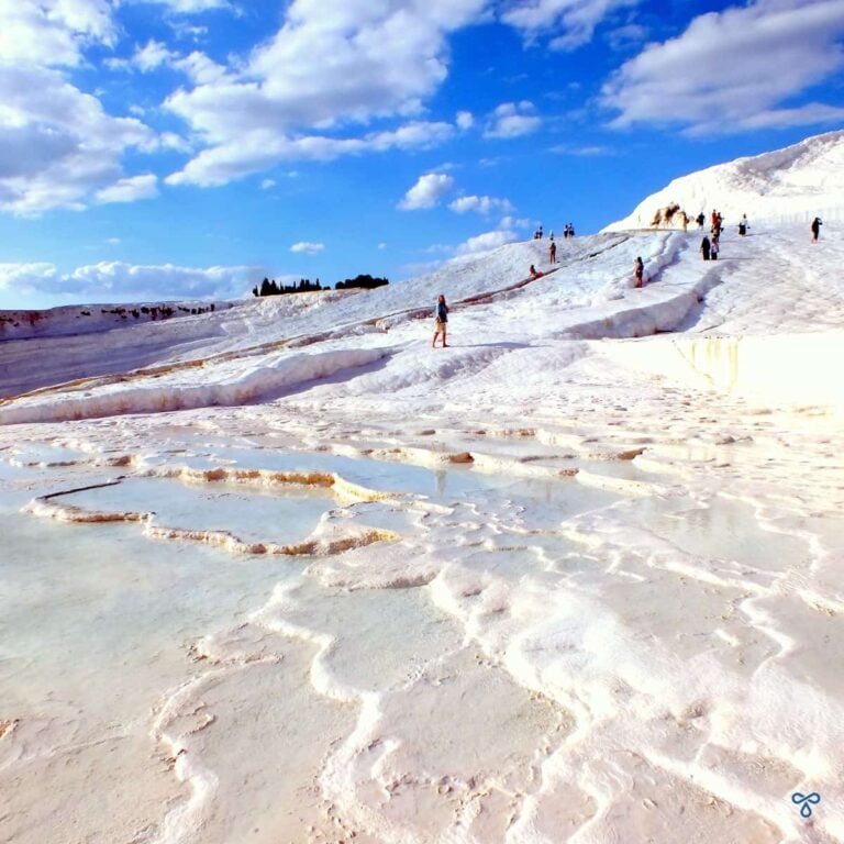 Pamukkale white travertines. People climb the travertines in the distance.