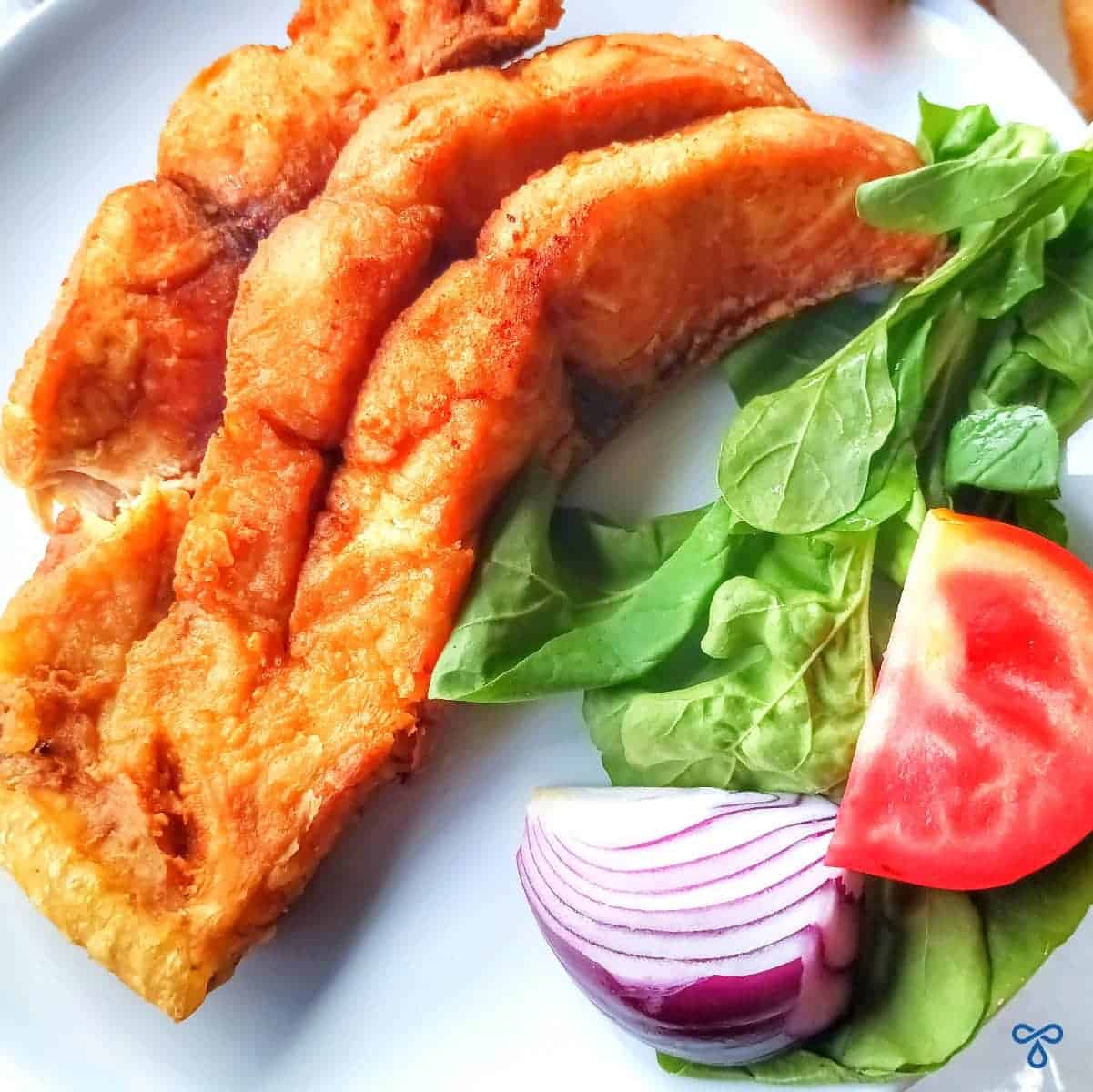 Deep fried battered carp served with a side of rocket, red onion and tomato.