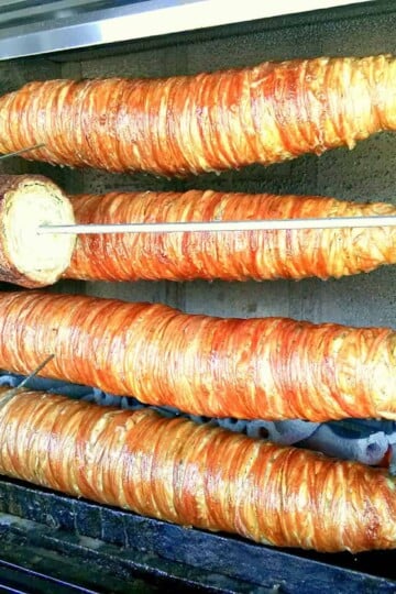 Lokum Kokorec Skewer. Four skewers with a strip of kokoreç roasting over coals.