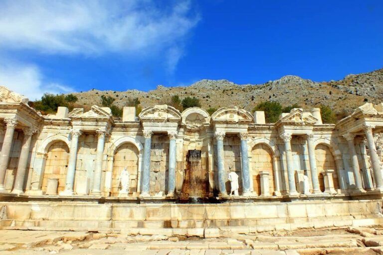 Sagalassos Antonine Nymphaeum - a long stone working fountain with water in the central area. Arches and columns line the fountain.