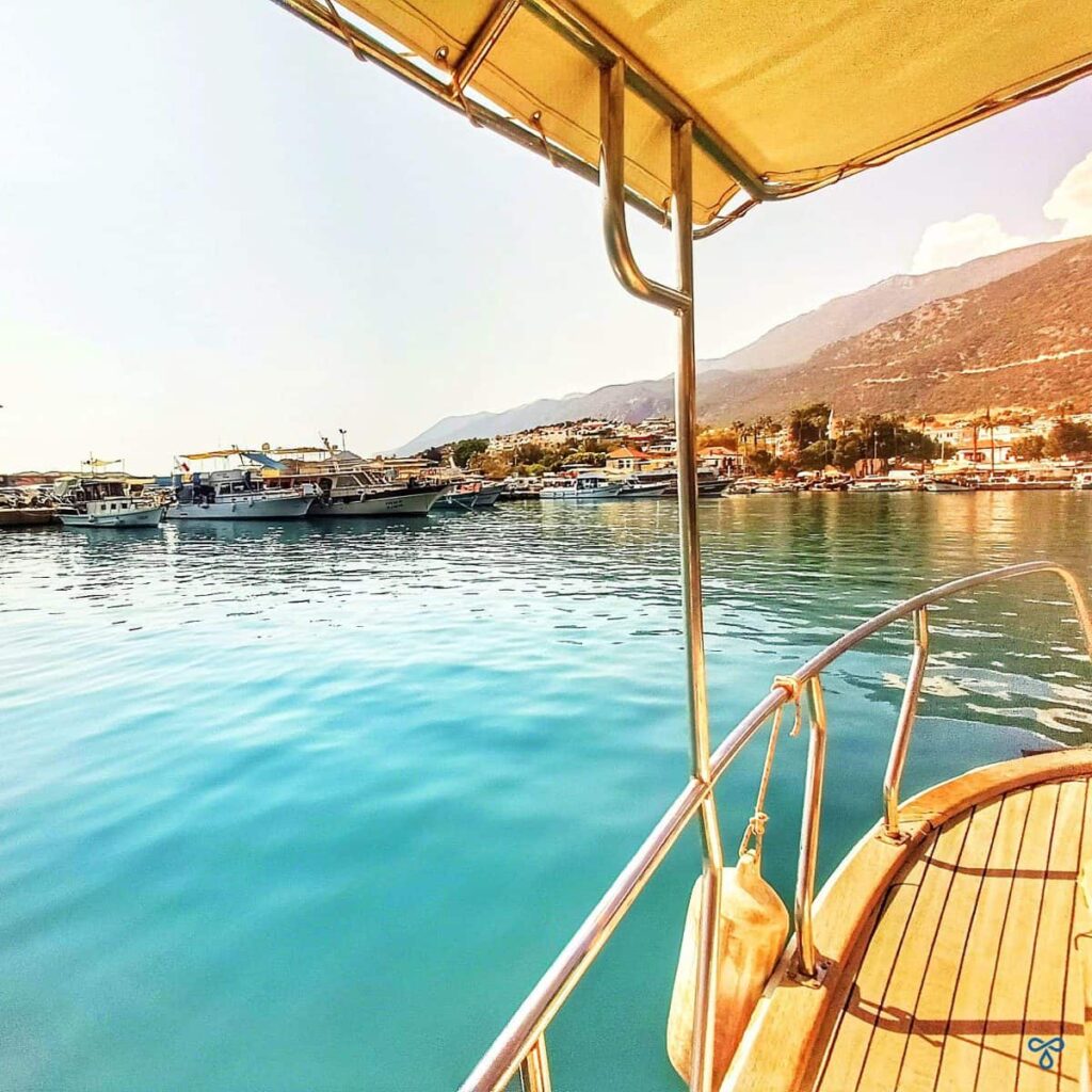 A view of Kaş harbour from a boat as it enters the harbour. The water is very calm and clear.