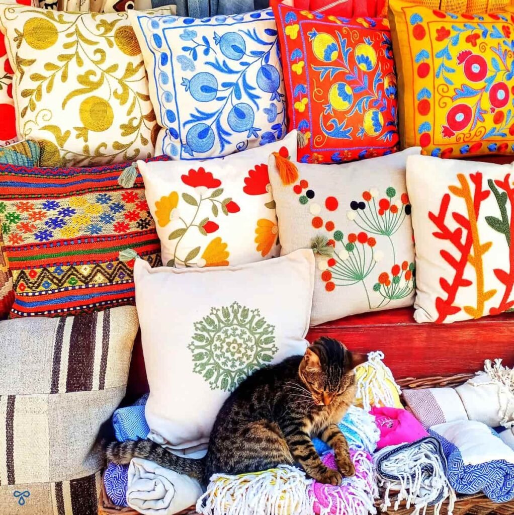 A display of decorative cushions in Kaş. A cat is sitting on one of the cushions.