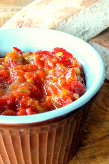 A ramekin dish with a homemade ketchup. Two slices of bread are in the background.