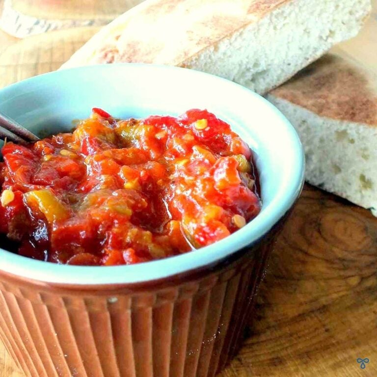 A ramekin dish with a homemade ketchup. Two slices of bread are in the background.
