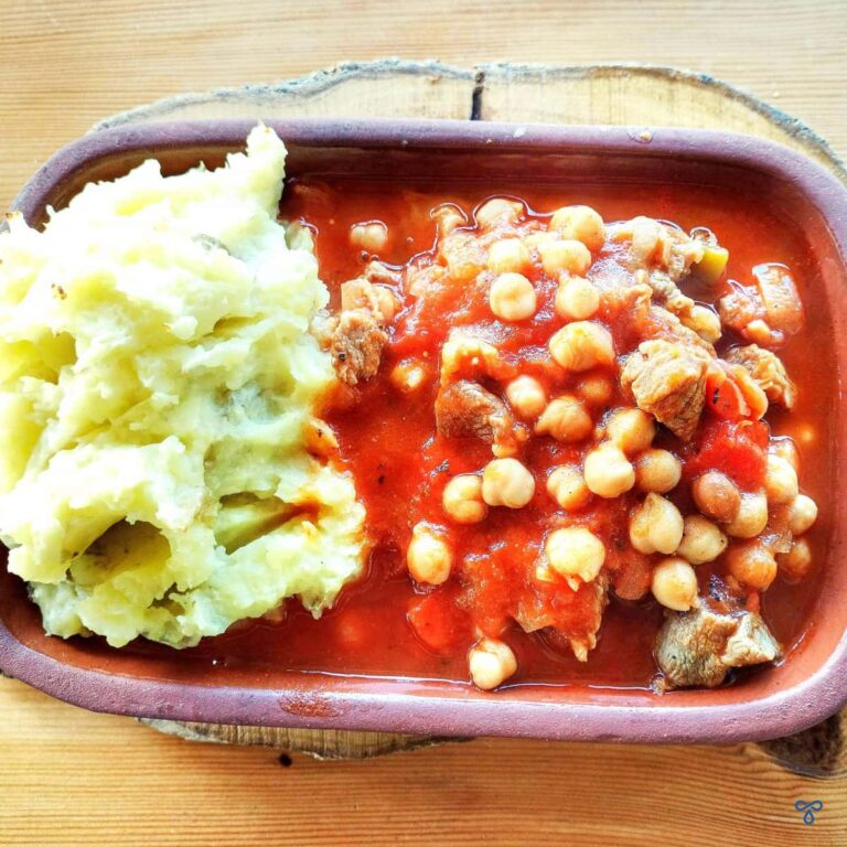 Turkish lamb and chickpea stew served in a rectangular clay pot with a side of mashed potatoes.