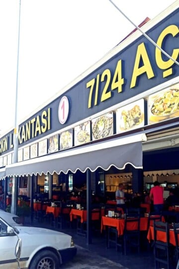 Exterior of Seçkin Lokantası in Fethiye. Rows of tables with orange tablecloths are outside. Canopies shade the tables.