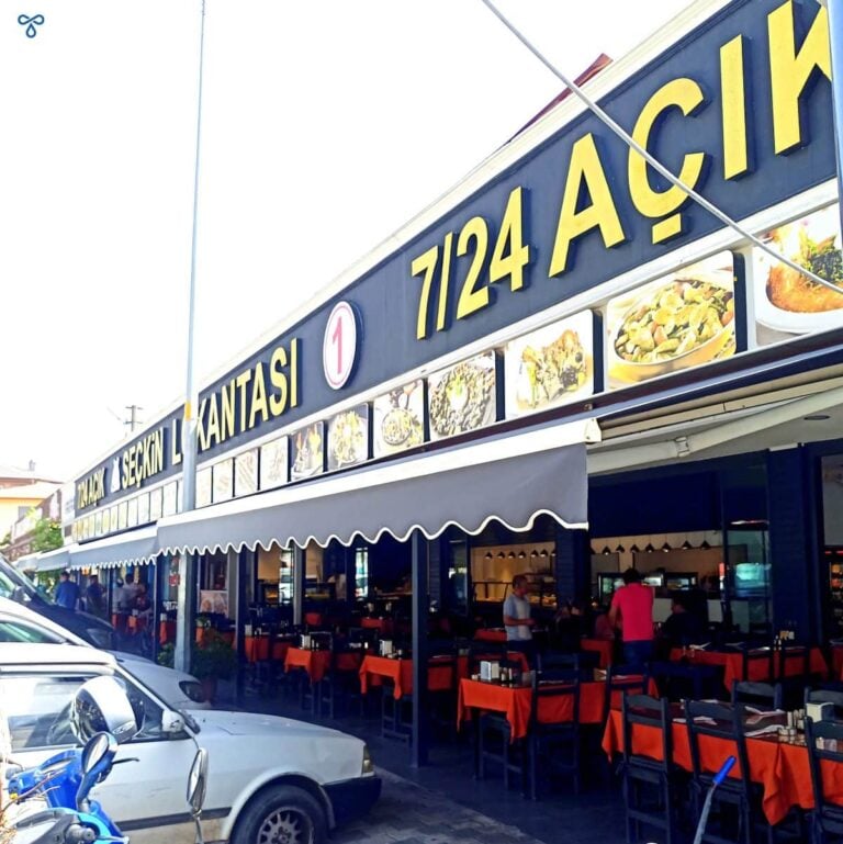 Exterior of Seçkin Lokantası in Fethiye. Rows of tables with orange tablecloths are outside. Canopies shade the tables.