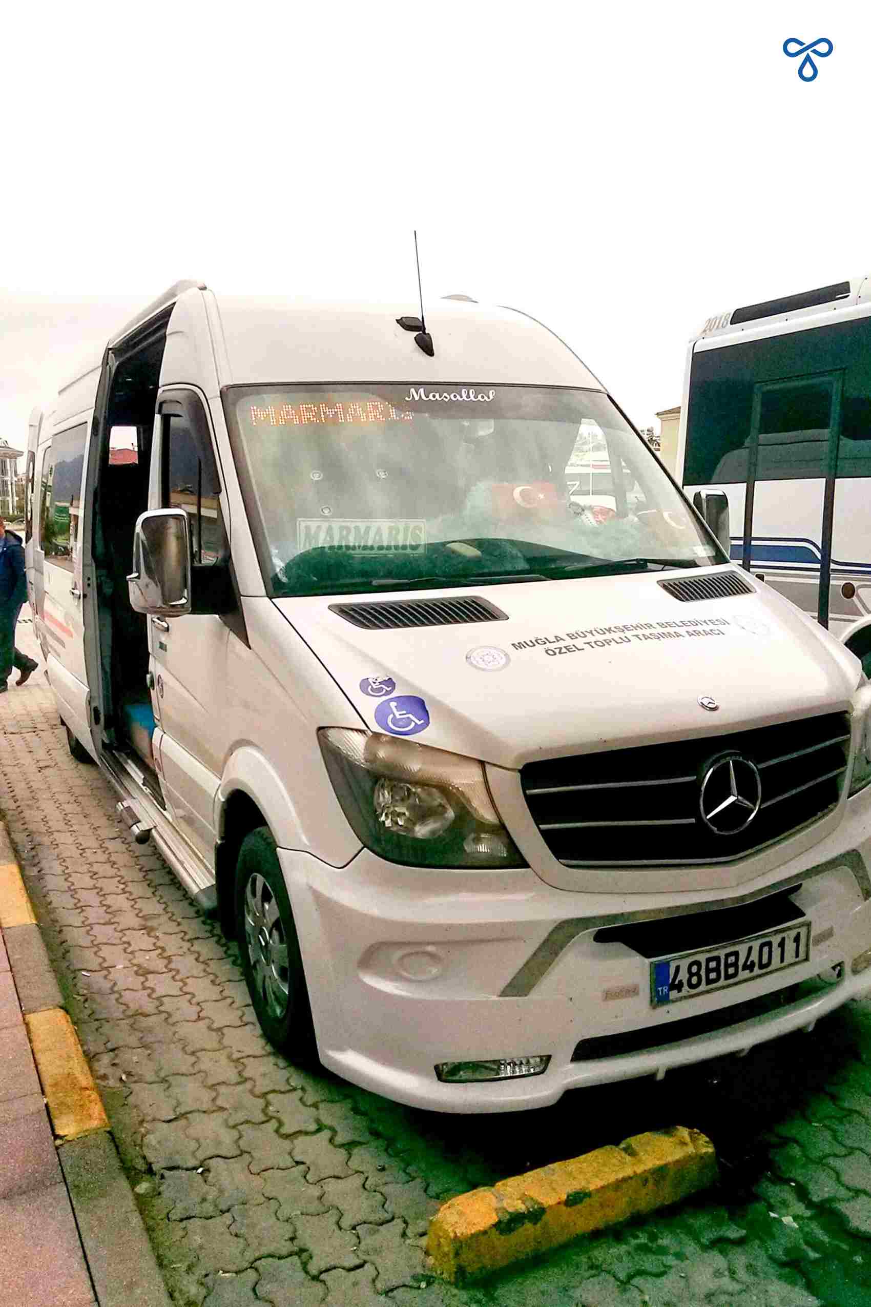 A white minibus parked up at Fethiye Bus Station. The destination reads Marmaris in the window.