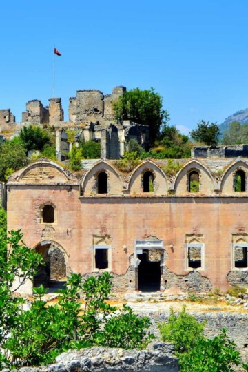 Kayaköy Upper Church viewed from up the hill. The church is framed by trees and the citadel sits above.