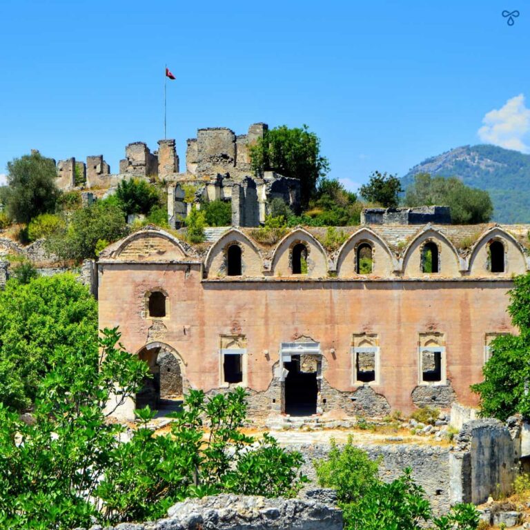 Kayaköy Upper Church viewed from up the hill. The church is framed by trees and the citadel sits above.