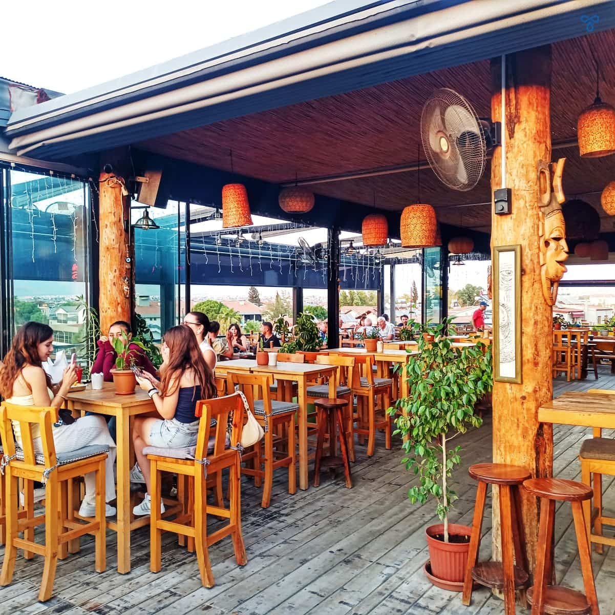 People sitting around wooden tables in the bar area.