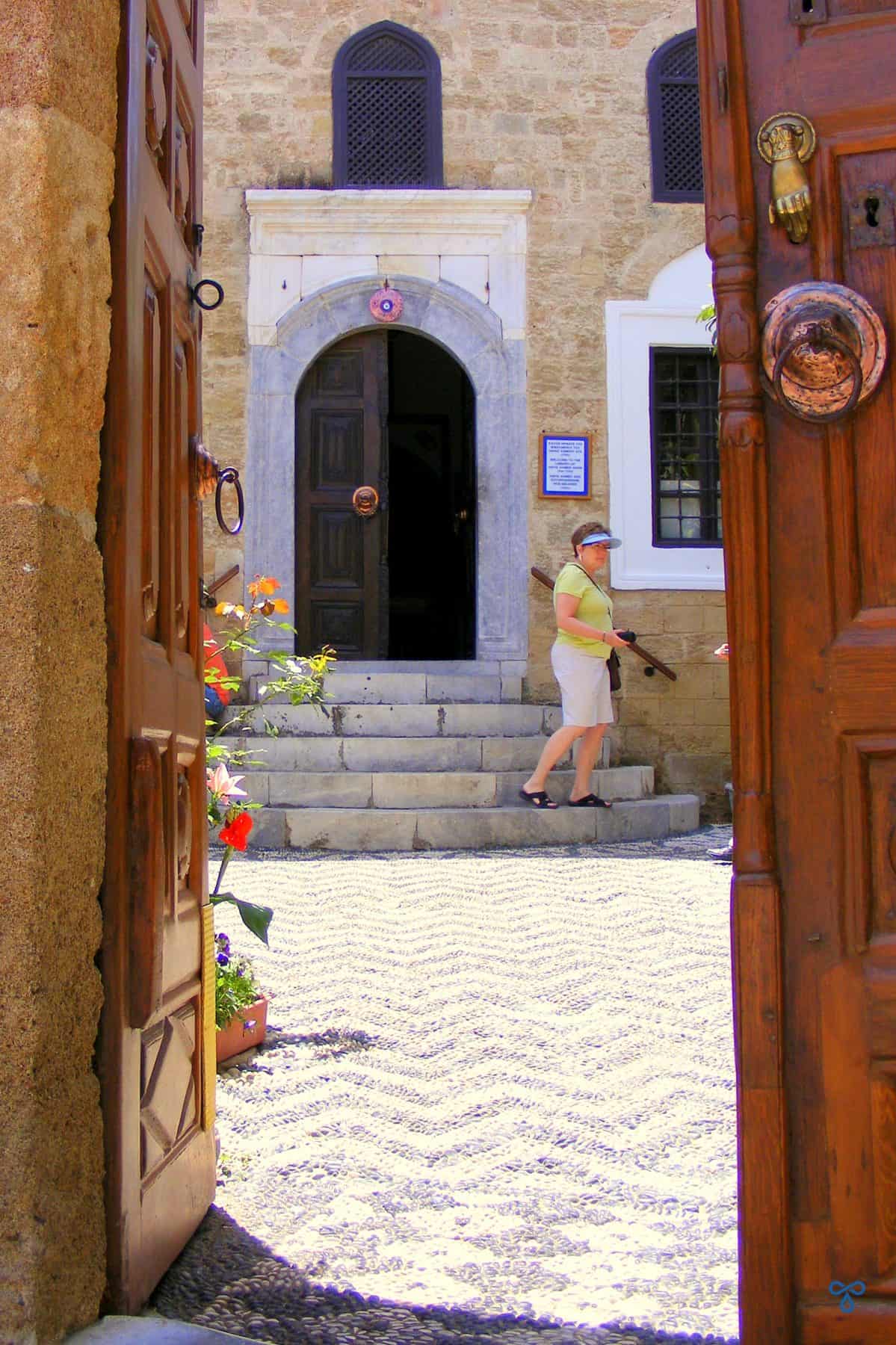 Looking over to the doorway of the Hafiz Ahmed Agha Library through the wooden gate. Black and white patterned pebbles cover the floor.