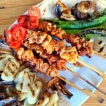 Four cooked chicken skewers served with griddled onion, green peppers, tomato and mushroom.