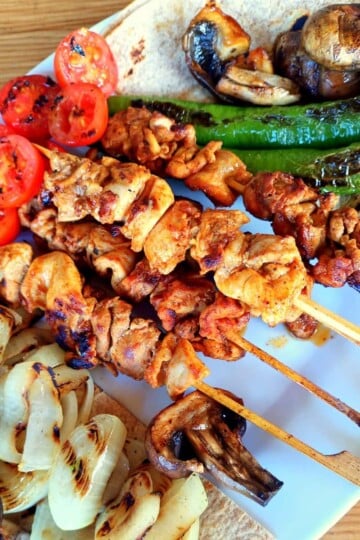 Four cooked chicken skewers served with griddled onion, green peppers, tomato and mushroom.