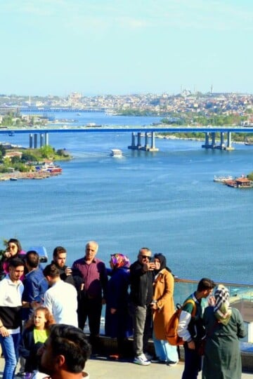 People taking photos of each other at Pierre Loti with the Golden Horn estuary and bridge in the background