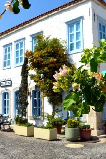 A whitewashed stone hotel with blue shutters