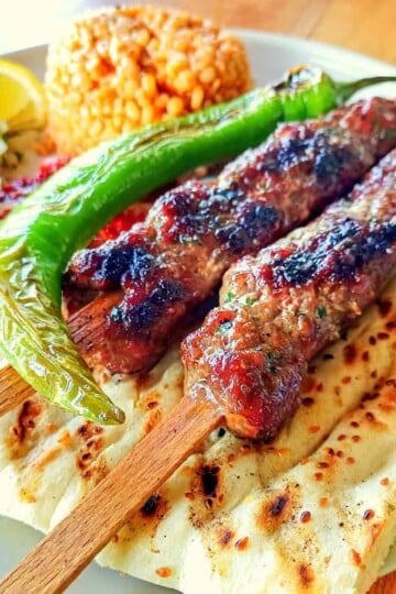 A plate serving of Adana Kebab and accompaniments